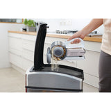 Aspirateur à main Black+Decker blanc utilisé pour vider la poussière dans une cuisine moderne.