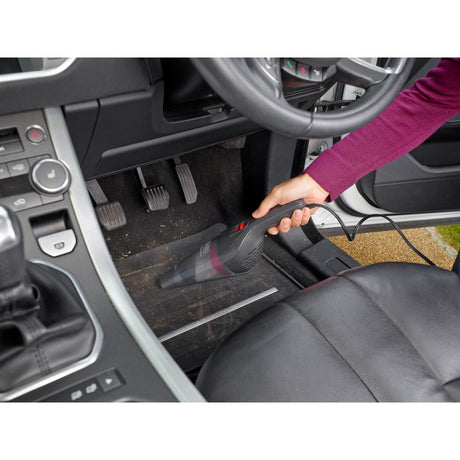 Aspirateur à main Black+Decker, type nettoyeur de voiture, couleur noir, en usage sur tapis de voiture.