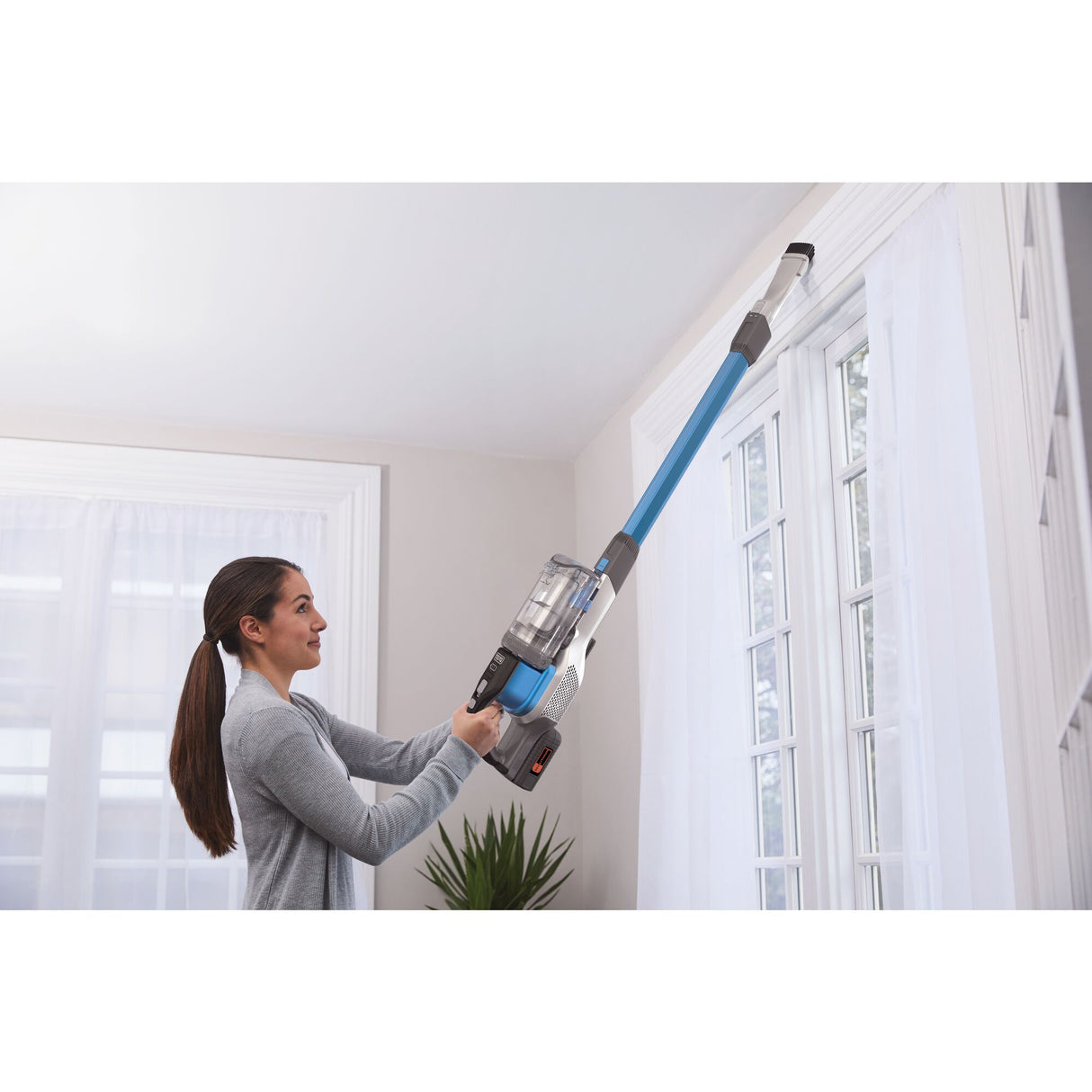 Aspirateur sans fil Hoover, balai aspirateur bleu, utilisé pour nettoyer le haut d'une fenêtre.