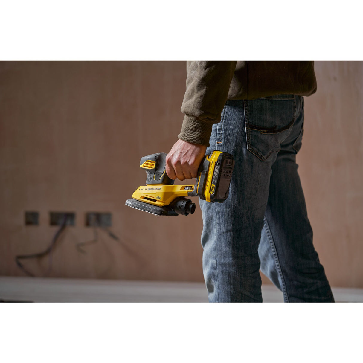 Ponceuse sans fil jaune Stanley Fatmax, outil électroportatif de couleur noire et jaune, tenue à la main.