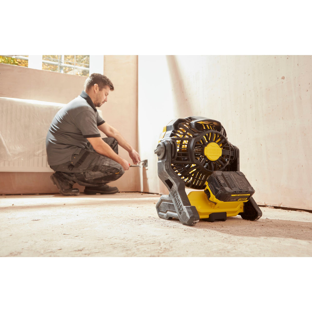 Ventilateur de chantier DeWalt, outil portable jaune et noir, utilisé dans une pièce en rénovation