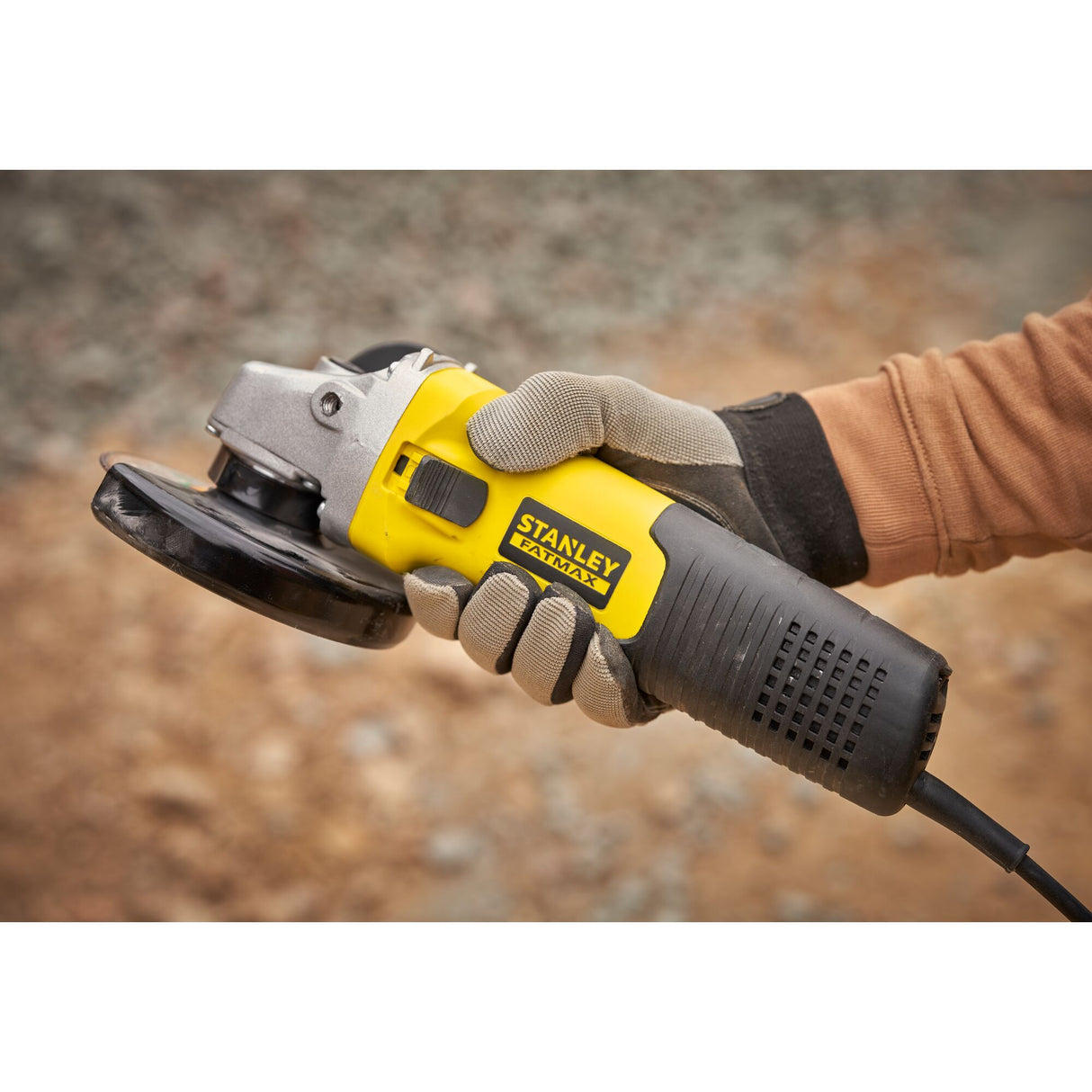 Meuleuse d'angle Stanley Fatmax, couleur jaune et noire, tenue en main avec gants.
