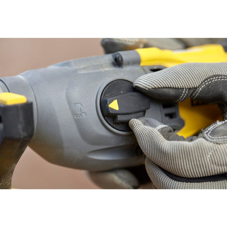 Perforateur DeWalt gris et jaune, commande rotative, utilisé avec un gant