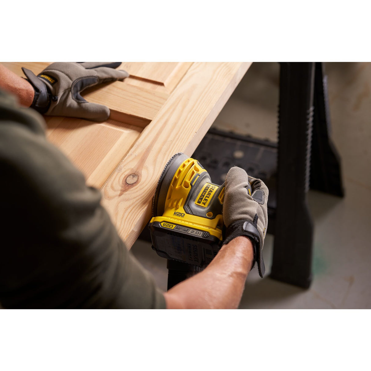 Ponceuse sans fil jaune Stanley utilisée sur bois, outil électroportatif.