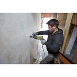Perceuse jaune Stanley, outil électroportatif, utilisée sur un mur, couleur noire et jaune.