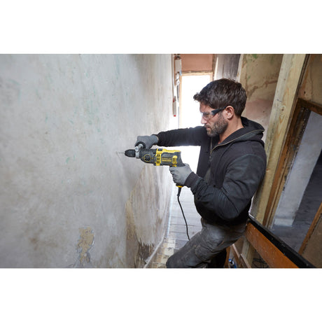 Perceuse jaune Stanley, outil électroportatif, utilisée sur un mur, couleur noire et jaune.