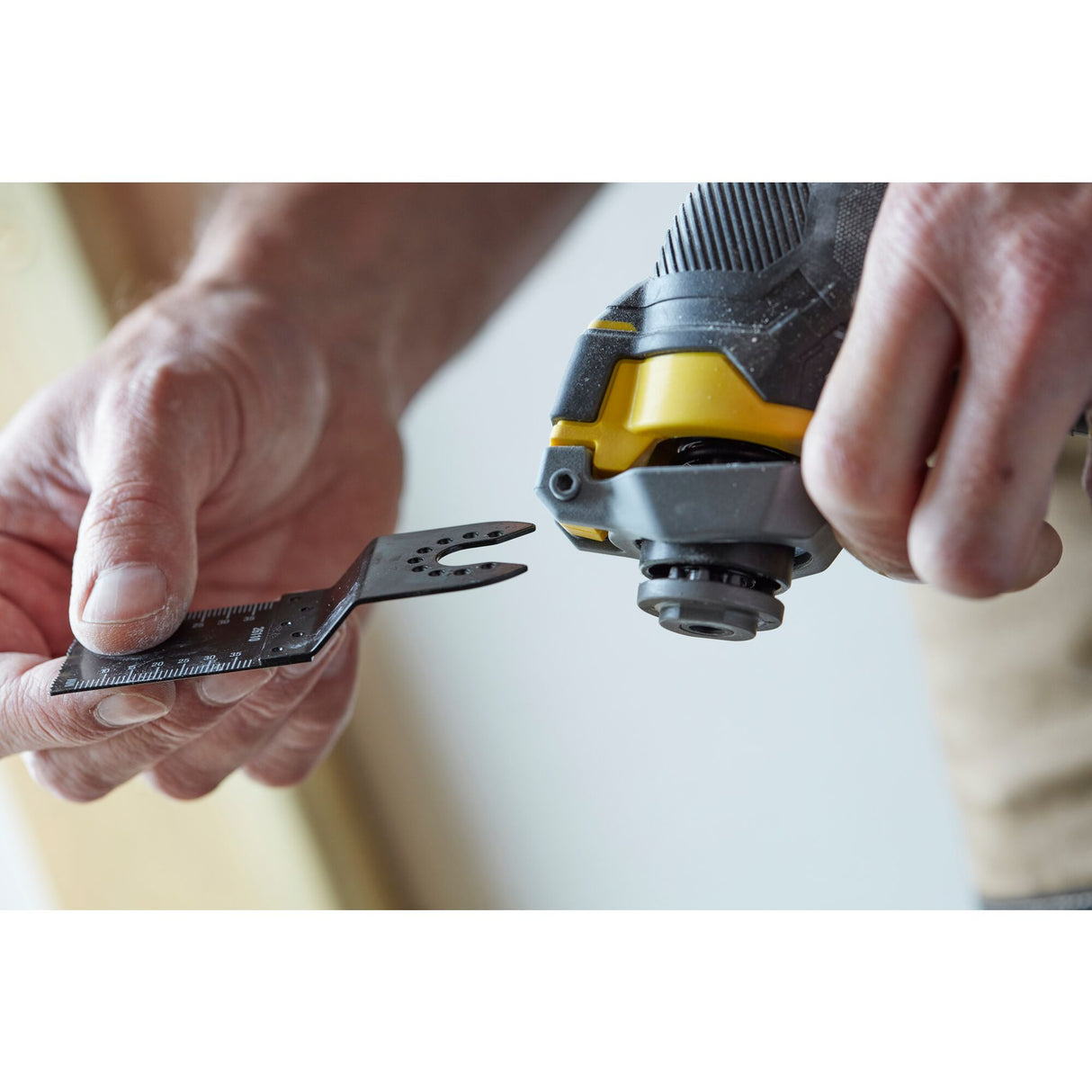 Outil multifonction DeWalt, noir et jaune, en main, lame de scie détachable.