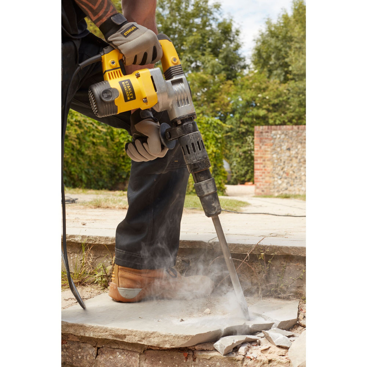 Marteau-piqueur Stanley jaune en action sur béton, outil électrique de couleur jaune.