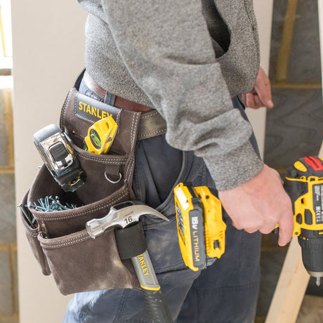 Ceinture porte-outils Stanley marron, contenant des outils jaunes et argentés, pour bricolage.