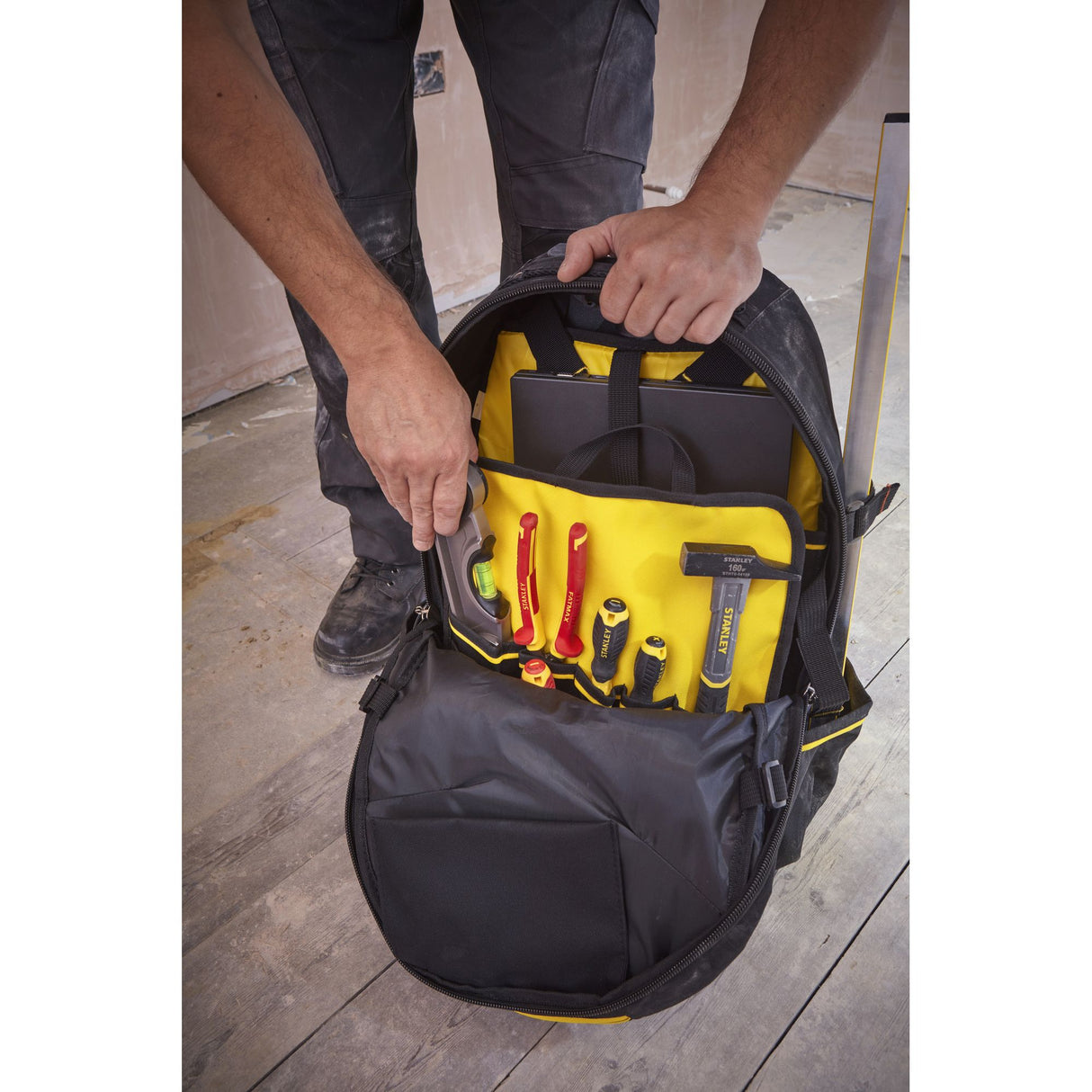 Sac à outils Stanley, sac à dos noir et jaune, organisé avec outils visibles.