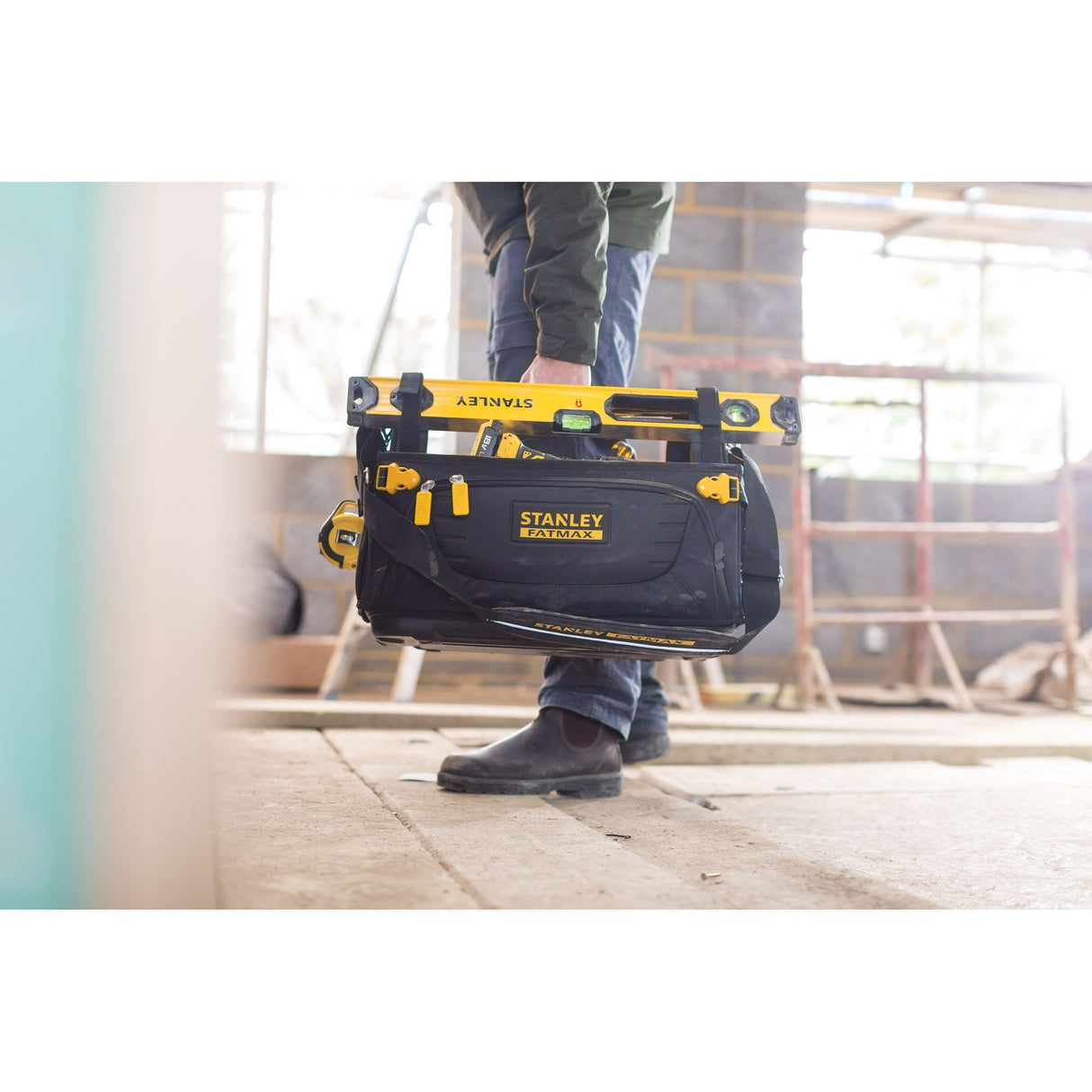 Sac à outils Stanley FATMAX noir et jaune, porté sur un chantier de construction