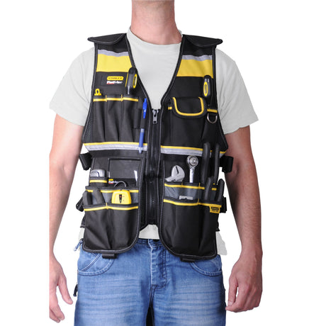 Gilet porte-outils Stanley noir et jaune, équipement pour outils, porté par un homme.