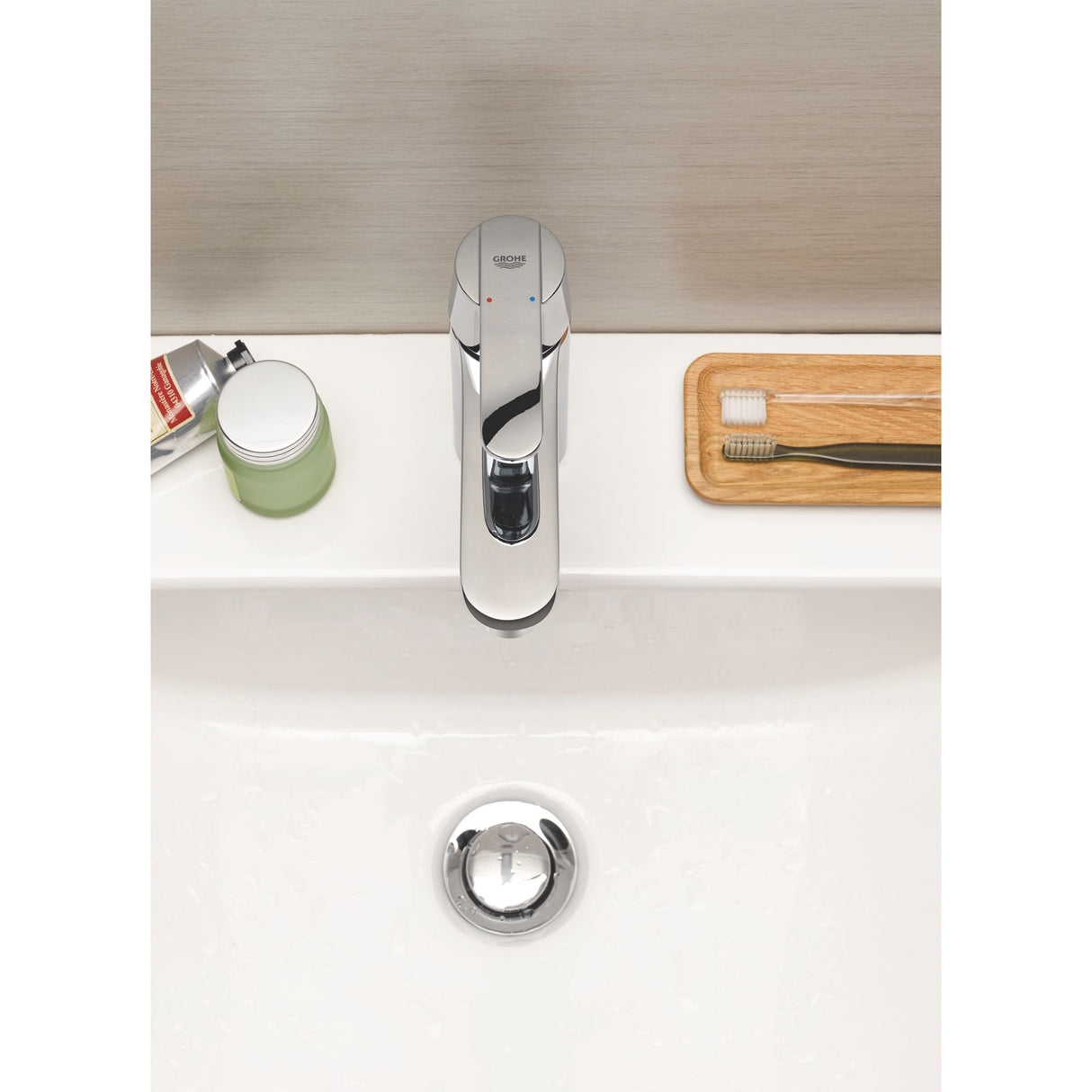 Mitigeur de lavabo Grohe, robinet chrome, design moderne sur vasque blanche.