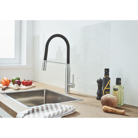 Mitigeur cuisine Grohe, couleur chrome et noir, installé sur un évier inox moderne.