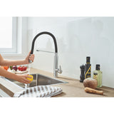 Mitigeur de cuisine Grohe, noir et chrome, sur évier moderne, mains rinçant un citron