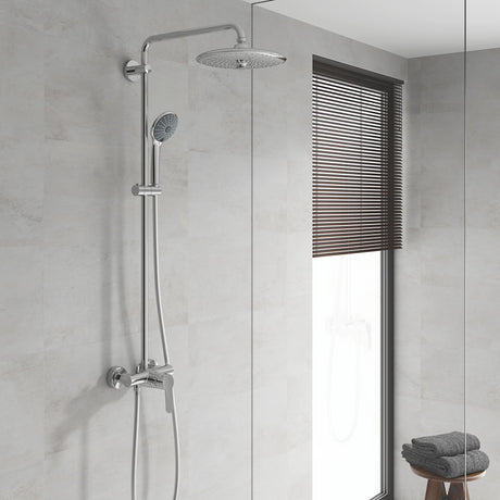Colonne de douche Grohe, chromée, avec pommeau rond sur mur de salle de bain claire.