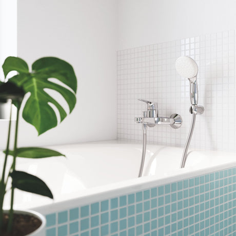 Mitigeur de baignoire chromé Grohe avec douchette, couleur argent, installé sur carrelage blanc.