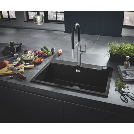 Évier de cuisine noir Grohe avec robinet moderne, plan de travail gris, légumes frais