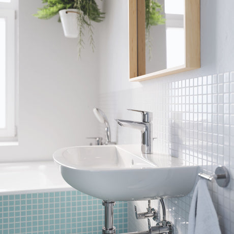 Mitigeur GROHE pour lavabo, finition chromée, installé sur un lavabo blanc dans une salle de bain moderne.