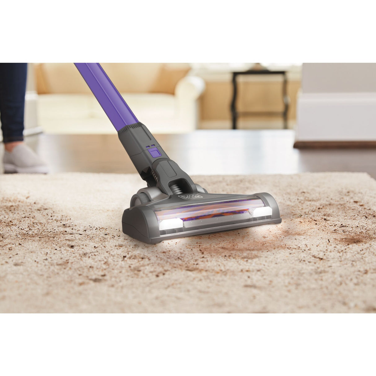 Aspirateur balai Black+Decker violet nettoyant un tapis beige