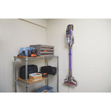 Aspirateur balai Black+Decker sans fil, violet, fixé au mur dans une buanderie.