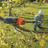 Élagueuse télescopique Black+Decker orange utilisée pour tailler une branche d’arbre