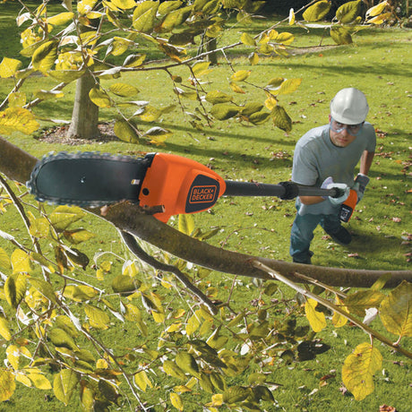 Élagueuse télescopique Black+Decker orange utilisée pour tailler une branche d’arbre